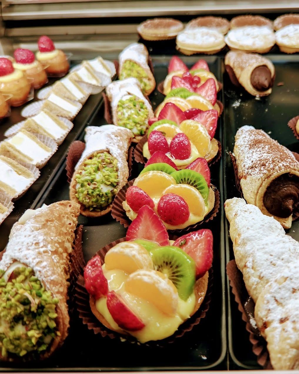 Vetrina della pasticceria con cannoli al pistacchio e crostatine alla frutta